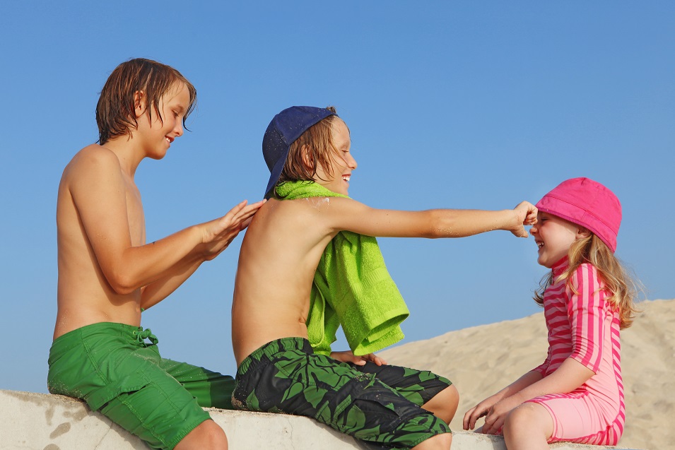 Children on beach applying sun protection