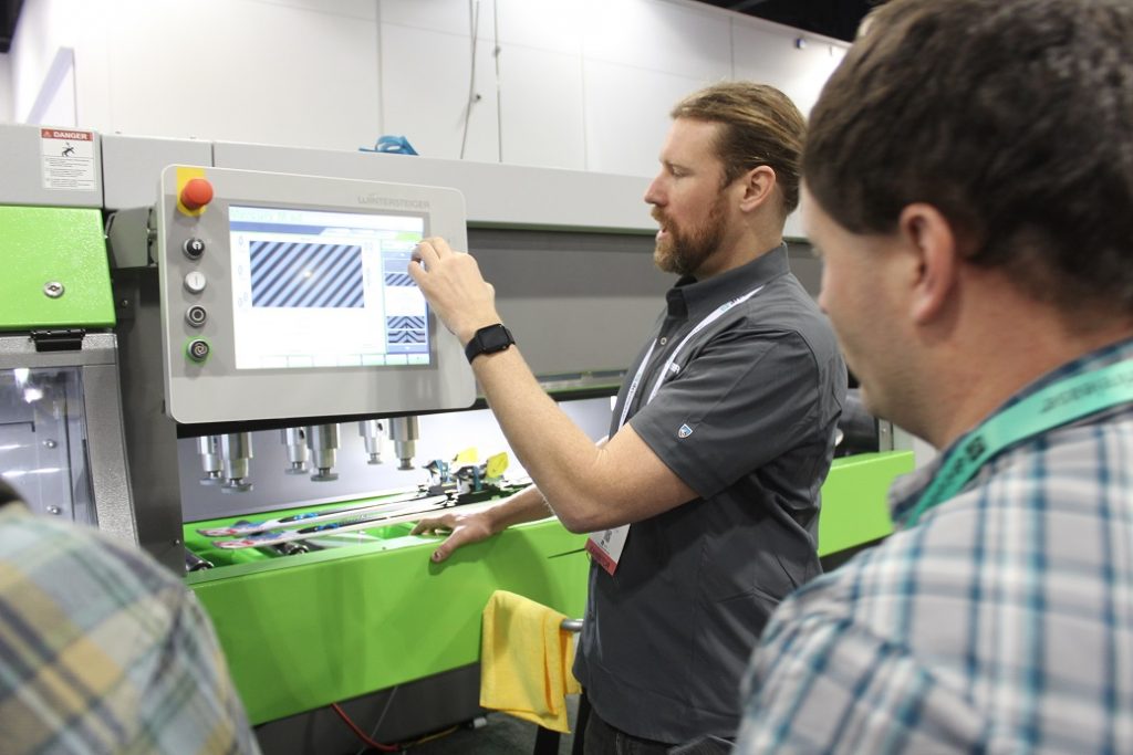 Demonstrating a machine that fine tunes skis and snowboards for rental shops